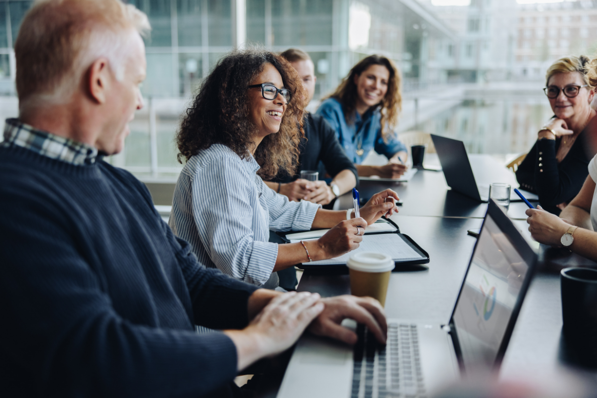 A group of people sit around a conference table conducting a business meeting..